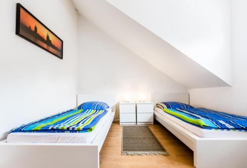 科隆科隆度假屋的配有白色墙壁和木地板的客房内的两张床