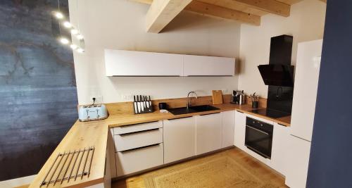 埃姆布能L'HIVERNET, grand Triplex neuf au cœur d'Embrun accès facile的厨房配有白色橱柜和木制台面