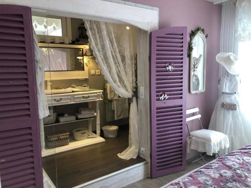 利克维Gite Riquewihr "C'est Beau la Vie Alsace"的卧室内的紫色门,配有梳妆台和镜子