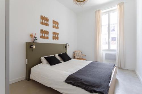 马赛Charmant T3 à proximité du Vieux-Port的白色卧室配有一张带黑色枕头的大床