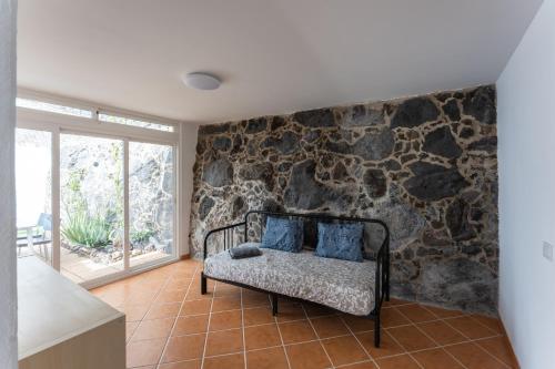 卡门港villa del mar puerto del carmen的一间设有石墙和一张带蓝色枕头的长凳的客房