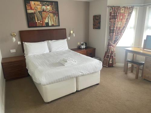 EdmondsleyThe Moorings Hotel的卧室配有白色的床、书桌和窗户。