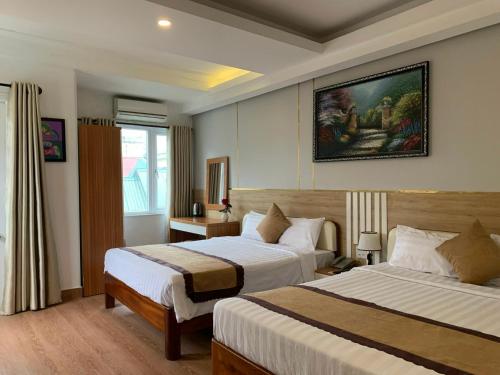 顺化Hong Thien 1 Hotel的酒店客房设有两张床,墙上挂有绘画作品