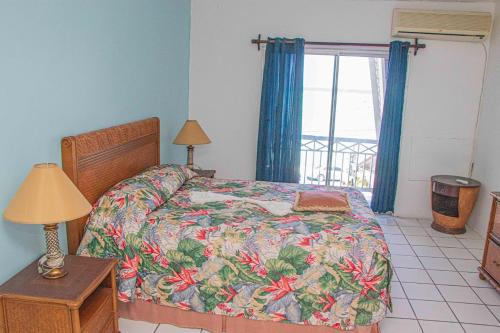 蒙特哥贝The Buccaneer的一间卧室配有一张带花卉床罩的床和窗户。