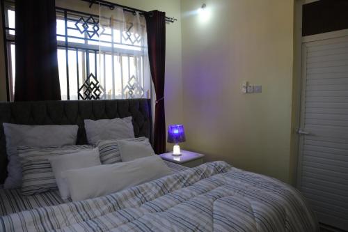 达累斯萨拉姆PEARL LULU MODERN BNB Homestay的一间卧室配有一张带一张桌子上紫色灯的床