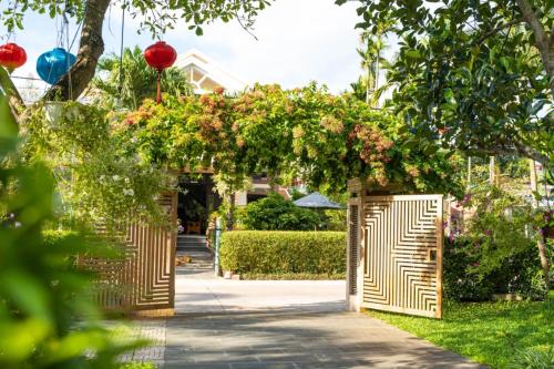 会安Chi Thanh Villa的花园入口,花园内有木拱门,鲜花盛开