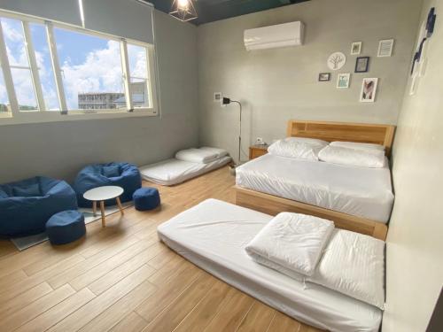 小琉球岛小琉球流浪背包客栈的一间卧室设有两张床、一张桌子和一个窗口
