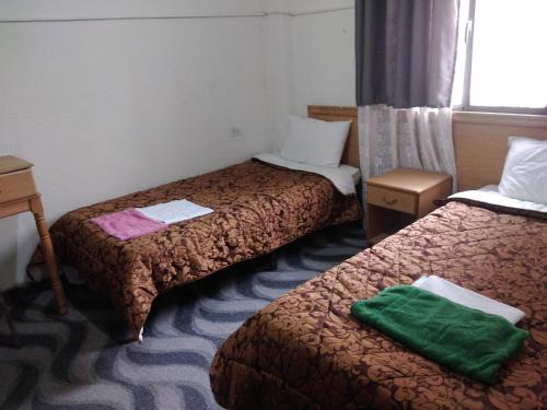 马达巴Queen Ayloa Hotel&Restaurant的酒店客房,配有两张带绿毛巾的床