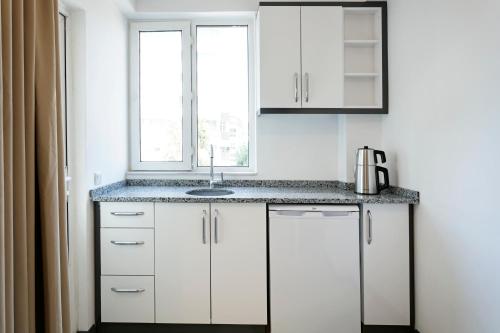 安塔利亚Marvida Happy Suites的厨房配有白色橱柜、水槽和窗户。
