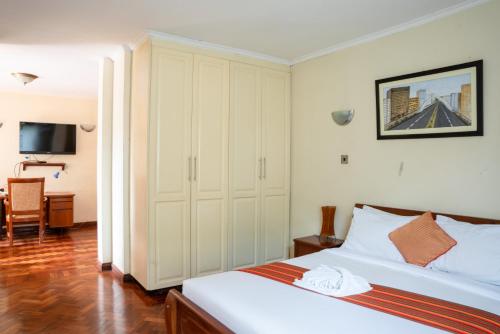 内罗毕dreamplace bed and breakfast Gigiri的一间卧室配有一张床、一张书桌和一台电视。