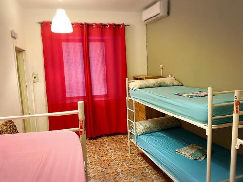 马拉加Cathedral Malaga Hostel的客房设有两张双层床和红色窗帘