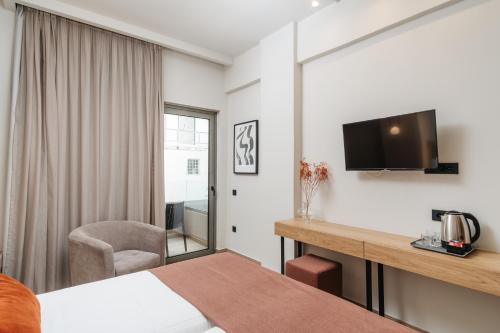罗希姆诺The City Hotel & Suites的酒店客房设有一张床、一张书桌和一台电视机。