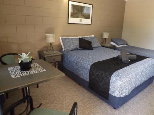 汤斯维尔太阳鸟汽车旅馆的一间卧室配有两张床、一张桌子和一张桌子。