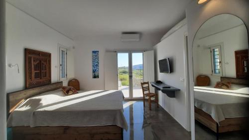 米克诺斯城Arion suites Mykonos的一间卧室设有两张床、一张桌子和一个窗口。
