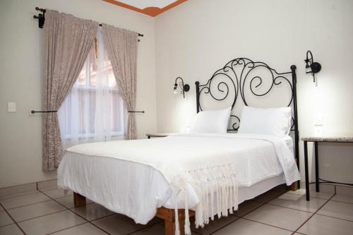 马斯科塔Encanto de la Sierra Hotel的卧室配有白色床和锻铁床头板