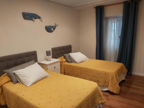 卢阿尔卡Apartamento BRUMA DE LUARCA的一间卧室设有两张带黄床单的床和窗户。