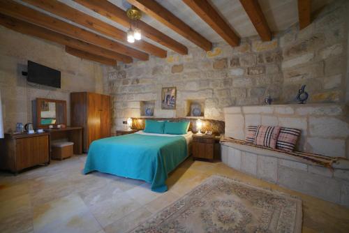 格雷梅萨尔奇姆窑洞公寓的一间卧室设有一张床和石墙