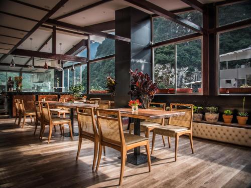 马丘比丘Jaya Machu Picchu Boutique Hotel的餐厅设有木桌和椅子以及大窗户。