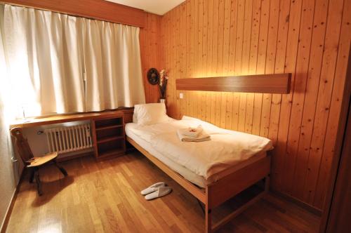 采尔马特艾米琳别墅酒店爱米莉公寓的卧室配有木墙内的一张床