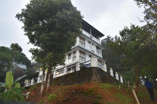 德维科拉姆MUNNAR TENT HILLS RESORT的山顶上的白色房子