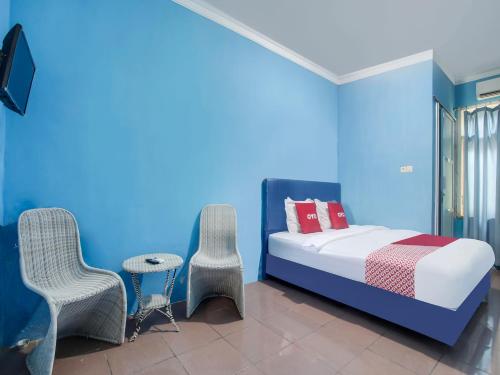 班达楠榜OYO 91005 Cottage Putra Mutun Beach的卧室拥有蓝色的墙壁,配有一张床和椅子