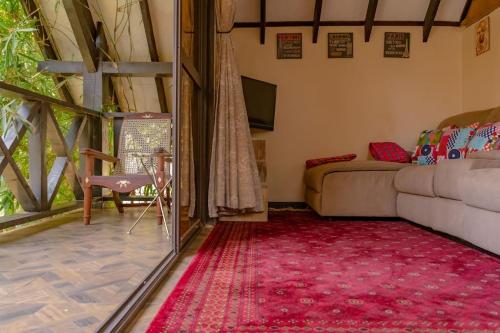 内罗毕The Annex at 64 : Cozy, rustic cottage/treehouse的带沙发和红色地毯的客厅