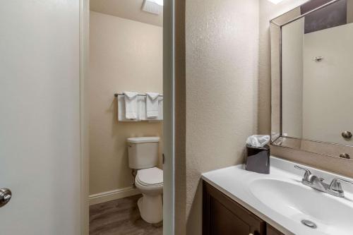安大略Rodeway Inn & Suites的浴室设有卫生间和带镜子的盥洗盆