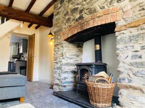 兰戈伦Abbey Cottage的带壁炉的客厅设有石墙