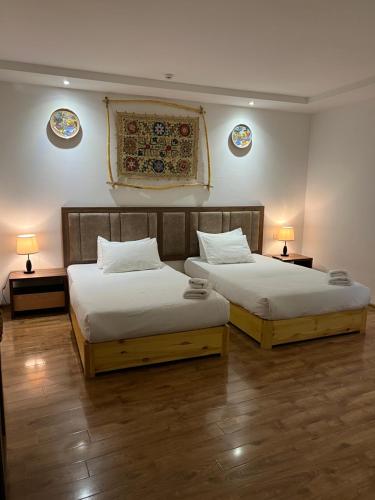 布哈拉利亚比之家酒店的两张床位于带两盏挂在墙上的灯的房间