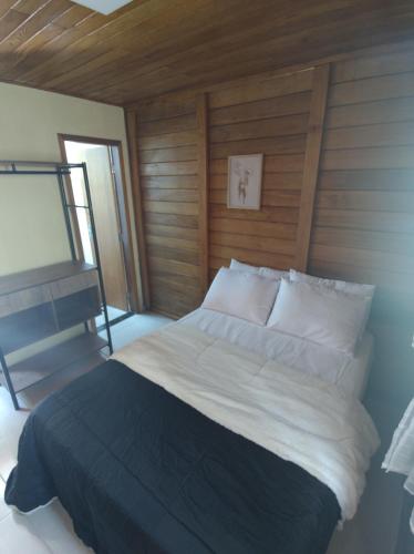多明戈斯马丁斯Chalés Schwambach的一间卧室设有一张带木墙的大床
