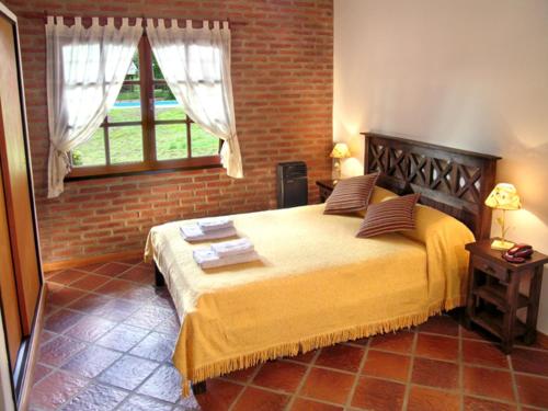 贝尔格拉诺将军镇Posada La Escondida的一间卧室设有一张带砖墙的大床