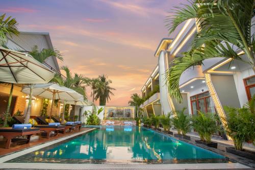 马德望Cambana La Rivière Hotel的棕榈树建筑中间的游泳池