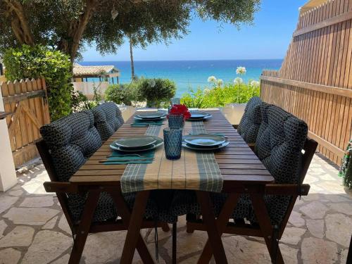 格利法达Just my dream beachfront Home 34 in Glyfada beach Corfu by New Era的一张带椅子的木桌和大海背景