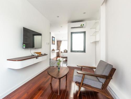 胡志明市Ngan Ha 2 Apartments的客厅配有桌子、椅子和电视