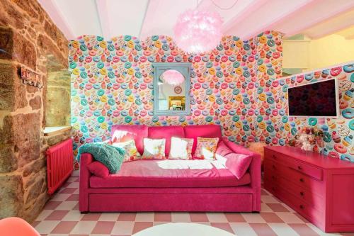 科尔库维翁La Suite Años 50 La casa Barbie Bañera chimenea的客厅配有粉红色沙发,客厅配有壁纸