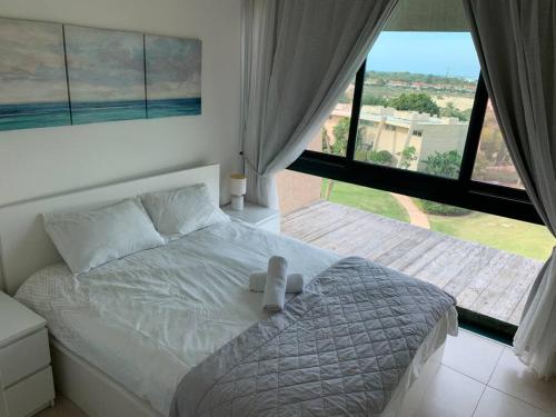 凯撒利亚Caesarea Magic的卧室设有一张白色的床和大窗户