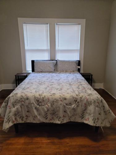 圣安东尼奥Luxurious 3 bedroom near downtown的一间卧室配有一张带花卉床罩的床和两个窗户
