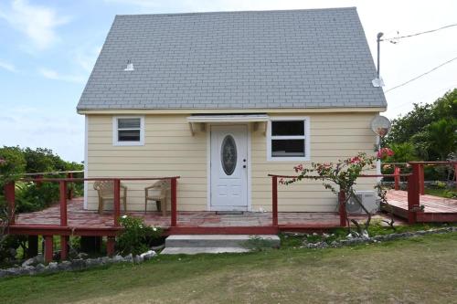 Gregory TownSea view Pointe的一座黄色的小房子,设有木甲板