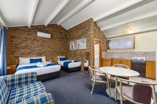 罗布Robe Central Motel的酒店客房带两张床和一张桌子以及椅子。