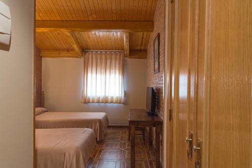 Castillo de GarcimuñozHotel-Restaurante La Sima的小房间设有两张床和窗户