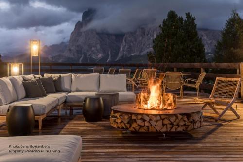 阿尔卑斯休斯山Paradiso Pure Living Vegetarian-Vegan Hotel的甲板上的火坑,配有沙发和椅子