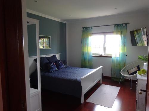 Vila ChãFerienhaus Casa do mar mit seitlichem Meerblick的一间卧室配有一张带蓝色床单的床和一扇窗户。
