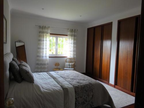 Vila ChãFerienhaus Casa do mar mit seitlichem Meerblick的一间卧室设有一张大床和一个窗户。