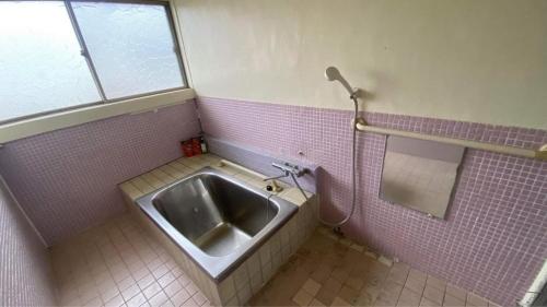 下关BRIDGE Share House的粉红色瓷砖浴室内的盥洗盆,浴室设有窗户