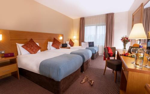 蒂珀雷里Great National Ballykisteen Golf Hotel的酒店客房配有两张床和一张书桌