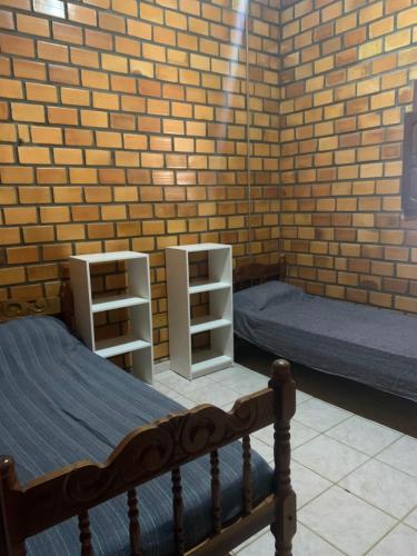 康德Cifa & Alê Hospedaria的一间卧室设有两张床和砖墙