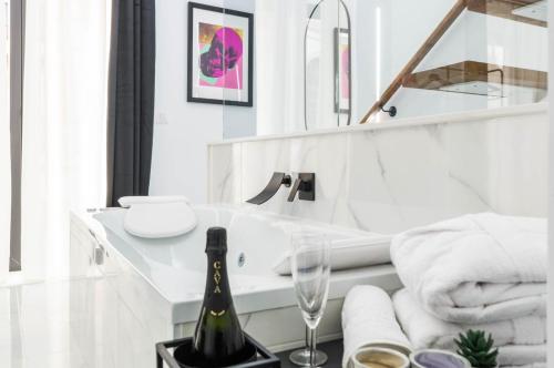 梅里达Apartamentos Élite - Art Collection - Andy的白色浴室,桌子上备有一瓶香槟