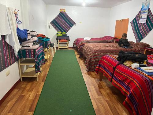普诺Hotel Wiñay Pacha Inn的一间设有三张床的客房,铺有绿色地毯