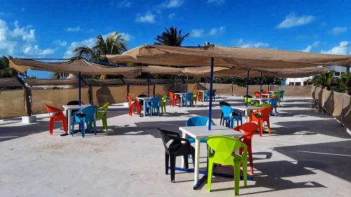 ChuburnáHotel Chuburna的一组桌子,有五颜六色的椅子和遮阳伞