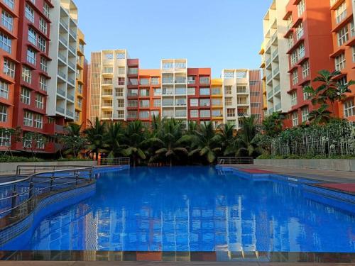 SancoaleGarden View 1 BHK2BR Appt., Rio De Goa TATA Housing的一座大型蓝色游泳池,位于部分建筑前